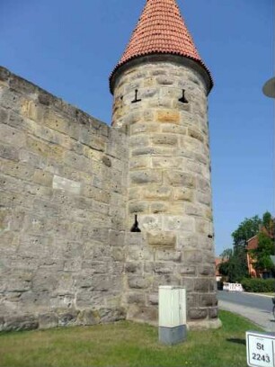 Nordwest-Rundturm von Norden mit verschiedenen Schießscharten und Mauersteinverband (Buckelquader) sowie anschließender Kirchhofmauer