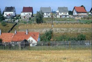 Reihe neuer Einfamilienhäuser, darunter aufgestellte Strohgarben