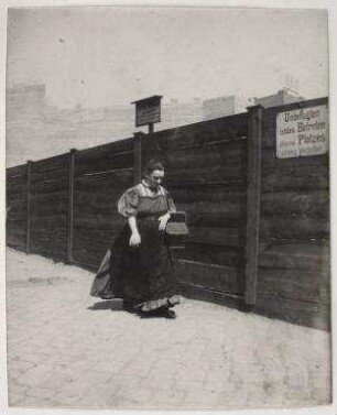 Ohne Titel (Frau mit Korb vor einem Bauzaun)