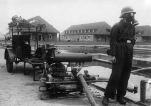 VW-Werk. Hier eine Luftschutzübung der Gefolgschaft. HJ-Mannen unter Schutzmaske an einer Wasserpumpe am Löschteich. Hier wird das Löschen von Bränden trainiert