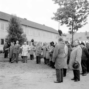 Ahrensburg: Hermann-Löns-Straße: Erweiterungsbau: Richtfest: vorn Gäste beim Hüteschwenken: dahinter Bäume: hinten Altbau