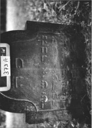 Grabstein 373 (Index: 99895792) Material: Sandstein Zustand: beginnt zu versinken Maße HxBxT: 67x58x11 cm Beschreibung: Stele mit eingezogenem Rundbogenabschluss: Grabstein 373A