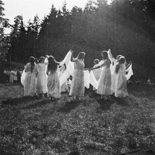 Frauen beim Tanz auf einer Wiese am Waldrand