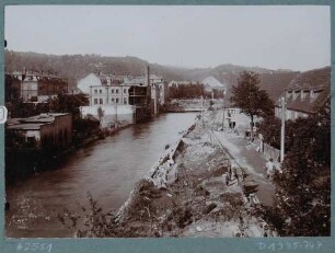 Blick über die Weißeritz auf die vom Hochwasser am 30./31. 7. 1897 zerstörte Möbelfabrik, Drechslerei und Holzbildhauerei Fritzsche & Schubert in Potschappel (Freital) mit Interimsbrücke
