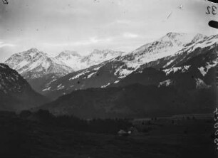 Häuser im Trettachtal : Häuser in einer Talsenke, dahinter aufragende Berge mit Neuschnee.