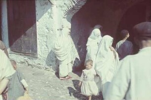 Reisefotos. Straßenszene mit verschleierten Frauen und kleinem Mädchen (vielleicht in Algier)