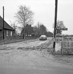 Glinder Weg: rechts Abzweigung Hinter den Höfen mit Straßenschild: dahinter Strommast: links Wohnhäuser mit Bäumen: in der Mitte Pkw