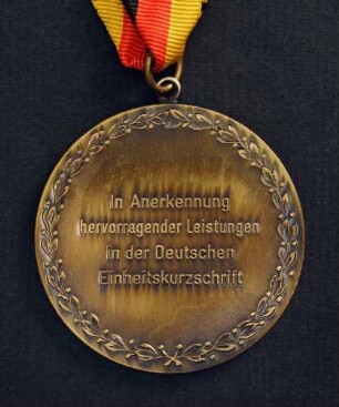 Bronzemedaille Deutsche Meisterschaften in Kurzschrift und Maschinenschreiben in Rodalben 1984 am schwarz-rot-goldenen Band : Sammlung Deutscher Stenografenbund. Bronzemedaille Deutsche Meisterschaften in Kurzschrift und Maschinenschreiben in Rodalben 1984 am schwarz-rot-goldenen Band. Messing, patiniert; Durchmesser 50 mm, Gewicht 48 g (1984; Deschler & Sohn, München). Dresden: SLUB R c 0538
