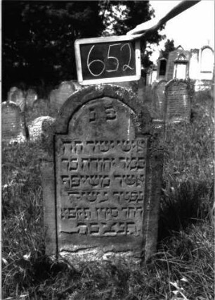 Grabstein 652 (Index: 100104941) Material: Sandstein Zustand: unten stark verwittert, abgeblättert, sonst gut erhalten Maße HxBxT: 96x51x6 cm Beschreibung: Stele, eingezogener Rundbogenabschluss, Schriftfeld eingetieft: Grabstein 652