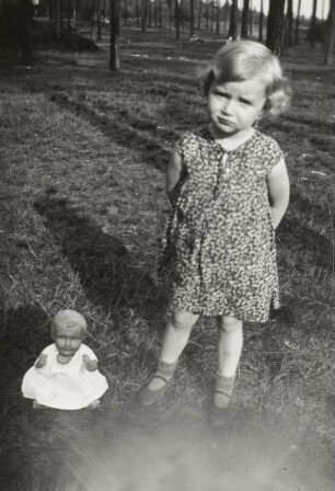 Kleines Mädchen mit Puppe auf einem Waldspaziergang