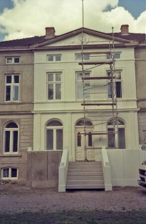 Dorfstraße 45: Hof Mönkhagen: Gutshaus: bei Restaurierung: Eingangsfront, Teilansicht: Mittelrisalit mit Flachgiebel, Eingangsportal, Freitreppe: davor Gerüst: teilweise Neuanstrich