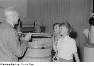 Drei Menschen an einem Stand mit Haushaltsgeräten, Herbstmesse 1953
