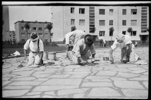 Arbeiter bei Pflastern einer Straße mit Steinplatten in der Wohnsiedlung "Rundling" in Leipzig