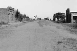Dorfstraße : Blick in eine verlassene Dorfstraße mit Gebäuden