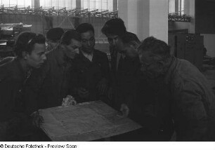 Mehrere Personen studieren eine technische Zeichnung beim Aufbau des chinesischen Pavillons für die Herbstmesse 1953
