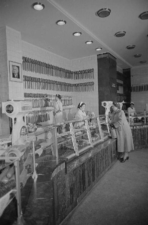 Kundin im Gespräch mit der Verkäuferin in einem Geschäft für Fleisch- und Wurstwaren