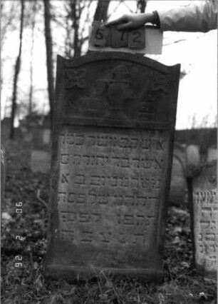 Grabstein 572 (Index: 100115334) Material: Sandstein Zustand: verwittert Maße HxBxT: 116x57x12 cm Beschreibung: Stele mit eingezogenem Segmentbogenabschluß, eingetieftes Schriftfeld mit geradem Abschluß Symbolik: Levitenkanne, Blüten: Grabstein 572