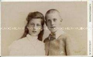 Porträtfoto - Geschwister (Mächen mit ofenen Haaren und weißem Oberteil, Junge mit weißem Kragen und Fliege)