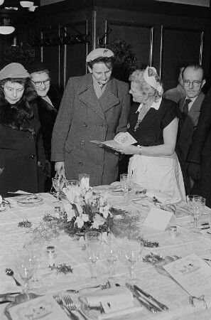 Besucherinnen und Servicepersonal vor einem festlich gedeckten Tisch in einer Küchenausstellung im Sachsenhaus