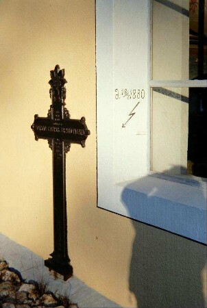 Eisenkreuz an der Kirchenwand, daneben Jahreszahl und Pfeil/Blitz mit Jahreszahl 1880