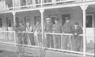 Selbstversenkung des Hochseepassagierdampfers "Columbus" am 19. Dezember 1939, acht Besatzungsangehörige im Internierungslager auf Angel Island, Kalifornien, über das Geländer einer Veranda gebeugt