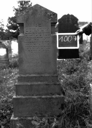 Grabstein 1007 (Index: 100103972) Material: Sandstein Zustand: gut erhalten Maße HxBxT: 131x44x16 cm Beschreibung: unten mehrfach getreppte Stele auf getrepptem Sockel, Dreiecksabschluss, seitlich durch Einzüge als nach oben weisener Pfeil gestaltet: Grabstein 1007