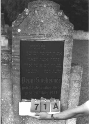 Grabstein 71 (Index: 99609707) Material: Kunststein?, Platte Granit? Maße HxBxT: 186x71x16 cm Beschreibung: Stele, mehrfach geschwungener eingezogener Segmentbogenabschluß, Seitenwangen, rechteckige Schriftplatte eingelassen, getreppter Sockel: Grabstein 71A