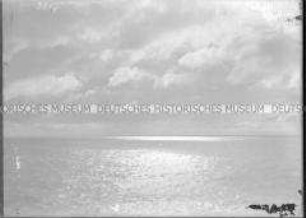 Mitternachtssonne hinter dunklen Wolken, Spiegelung im ruhigen Meer, Nordlandreise, Norwegen