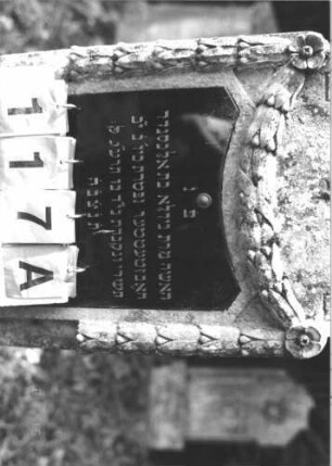 Grabstein 117 (Index: 100106420) Material: Sandstein, Schriftplatte Glas Zustand: leicht verwittert Maße HxBxT: 128x47x18 cm Beschreibung: Stele, Abschluß Sonderform, Schriftplatte Sonderform, Feston, Sockel Symbolik: Feston: Grabstein 117A