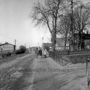 Oldesloer Straße: Kreisstraße nach Barkhorst mit Kopfsteinpflaster vor Ausbau: Ortsausgang: in der Mitte Schulkinder: rechts Bäume: dahinter Bauernhaus und Siedlungshäuser: links hinten Bauernhaus