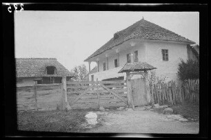 Câmpulung (Rumänien): Anwesen mit hoher Veranda und Scheune hinter einem Bretterzaun ("in Câmpulung")
