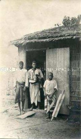 Zwei Männer und ein Junge vor der Küche der Station Molundu