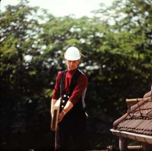 Zimmerer mit Holzbohle auf einem Gerüst