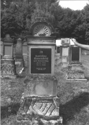 Grabstein 57 (Index: 99609693) Material: Sandstein Zustand: Schriftplatte vermutlich Ersatz Maße HxBxT: 207x64x28 cm Beschreibung: Stele, Abdeckplatte, Aufsatz mit eingezogenem Rundbogenabschluß, im Bogen Muschelwerk, Verdachung, Mittelerhöhung, Aufsatz fehlt, rechteckige Schriftplatte eingelassen, getreppter Sockel, unten Rusticaimitat Besonderheit: Schriftplatte vermutlich ersetzt: Grabstein 57