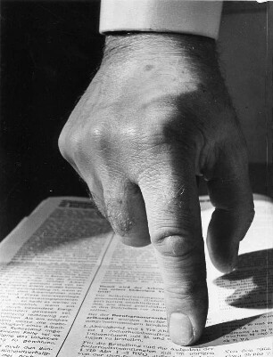 Gesten. Mit dem Finger wird auf eine Textpassage einer Unfallverhütungsvorschrift gezeigt