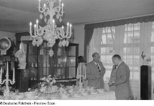 Personen an einem Stand mit Porzellanwaren sowie ein Scheinwerfer, Herbstmesse 1953