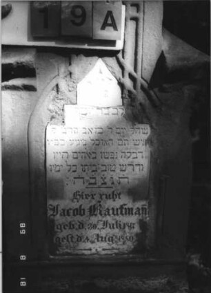 Grabstein 19 (Index: 100109162) Material: Sandstein und Marmor Zustand: stark verwittert, Schrifttafel zerbrochen und repariert Maße HxBxT: 129x72x31 cm Beschreibung: Stele auf Sockel, Abschluß Sonderform, Schrifttafel eingesetzt mit Maßwerk, Abschluß Sonderform Besonderheit: unehelich: Grabstein 19A