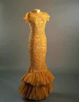 Sehr enges Abendkleid aus goldgelber Spitze mit Plisseerüschen am Saum (Archivtitel)