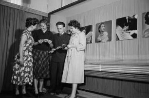 Vier Personen begutachten auf der Leipziger Herbstmesse 1955 Schmuck