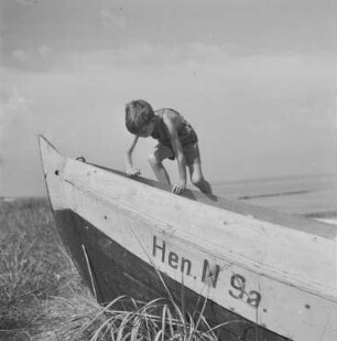 Das Kind der Gremmlers klettert in ein Ruderboot, das auf dem Trockenen liegt
