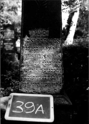 Grabstein 39 (Index: 100110020) Material: Granit Zustand: leicht verwittert Maße HxBxT: 188x37x37 cm Beschreibung: Obelisk, getreppter Sockel Symbolik: Palmwedel: Grabstein 39A