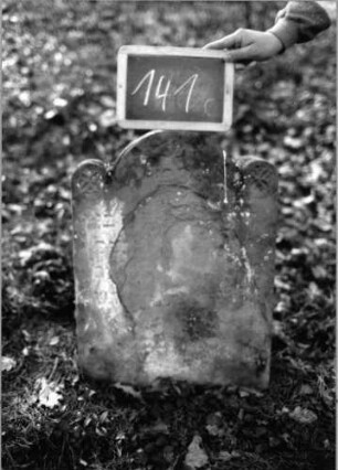 Grabstein 141 (Index: 100090437) Material: Sandstein Zustand: abgeblättert mit fast völligem Textverl. Maße HxBxT: 63x46x15 cm Beschreibung: Stele, eingezogener Segmentbogenabschluß mit runden Akroteren Symbolik: Blüten in den Akroteren: Grabstein 141