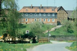 Blick über Senke im Dorf, links Spielplatz, hinten sehr großes Bauernhaus