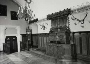 Schloss Kuckuckstein, Rittersaal mit Kamin, Standuhr und Schrank vor Wandvertäfelung, Ende 19. Jh.