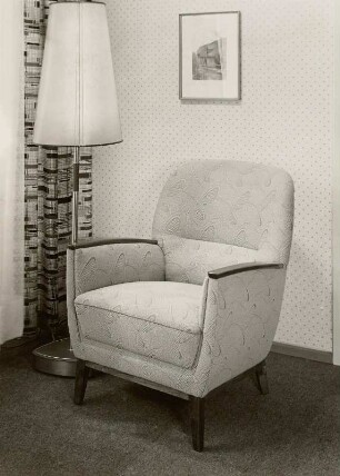 Armlehnsessel : Armlehnsessel (1956) in Ausstellungskoje neben Stehlampe und vor Gardine und Tapetenstreifen
