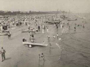 Ostseebad Ahlbeck. Strandleben. Badende und zahlreiche Strandkörbe und Fischerkähne am Sandstrand.
