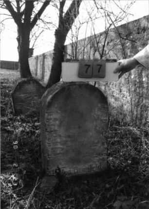 Grabstein 77 (Index: 100116221) Material: Sandstein Zustand: stark verwittert mit fast völligem Textverlust Maße HxBxT: 65x40x21 cm Beschreibung: Stele mit Rundbogenabschluß: Grabstein 77