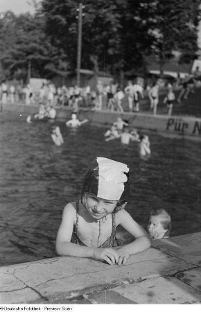 Portrait eines kleinen Mädchens in Badebekleidung am Beckenrand im Freibad