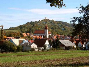 Ansicht von Süden mit Kirche (Gotische Gründung) zu erhöhter Lage am Ortsrand sowie Bergkapelle (Romanische Gründung - Barocker Neubau) im Hintergrund in Übersicht