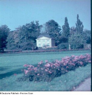 Blick über ein Wiesenstück mit Rosenbeeteinfassung gegen Kavaliershaus